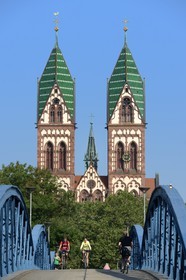 Germany, Baden-Wurttemberg, Freiburg im Breisgau, cyclist on the blue bridge (wiwili-bridge) and the Sacred Heart of Jesus Church (Herz-Jesu-kirche) in the background