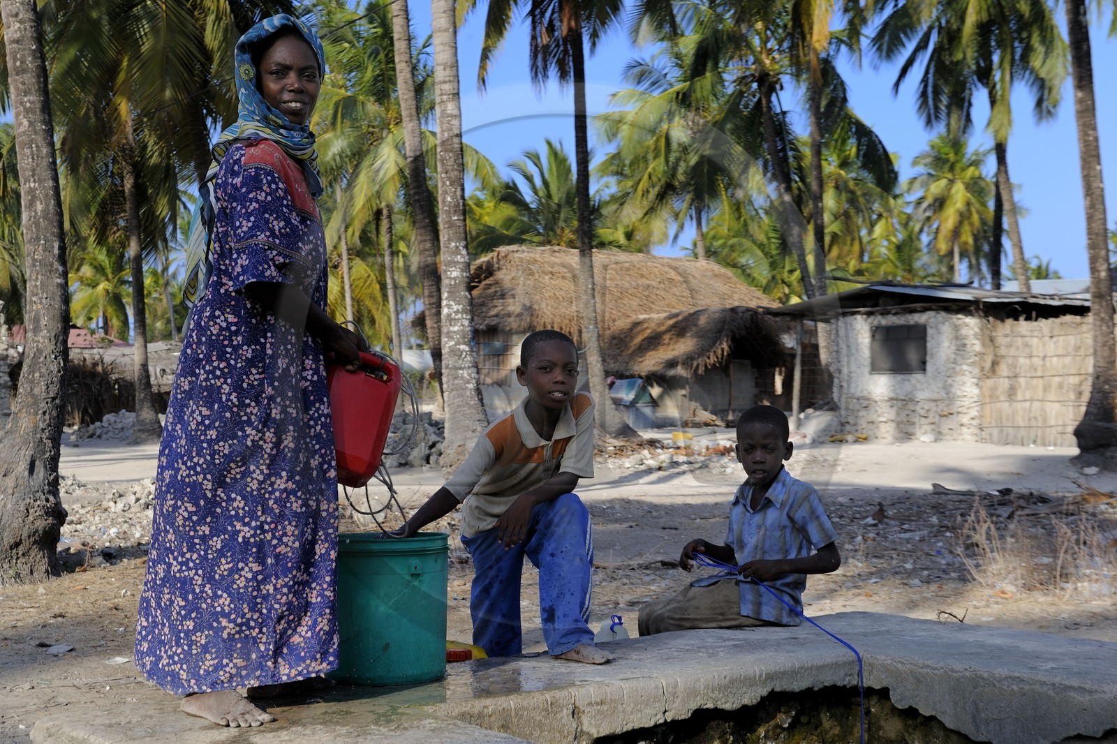 Tanzanie, Zanzibar, côte Sud-Est, famille tirant de l'eau au puit de Pingwe