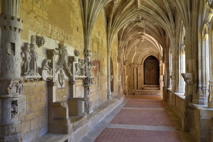 France, Dordogne (24), Périgord Noir, Le Buisson-de-Cadouin, abbaye de Cadouin, étape sur le chemin de Compostelle, site classé Patrimoine Mondial de l'UNESCO, le cloitre du XVe siècle, bas-relief de la passion du Christ, le banc des moines avec le siège de l'Abbé et Porte Romane en arrière plan