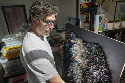 France, Cote d'Or, Dijon, Artist Aymeric Gillet, aka M'Brick, in his studio filled with crates of multicolored Lego used to create giant pixelated paintings inspired by pop culture