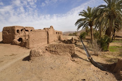Iran, Province d'Ispahan, désert du Dasht-e Kavir, l'oasis d'Arousan dans la région de Khur et Biabanak, ruine de maisons en terre crue et canal d'irrigation des champs cultivés