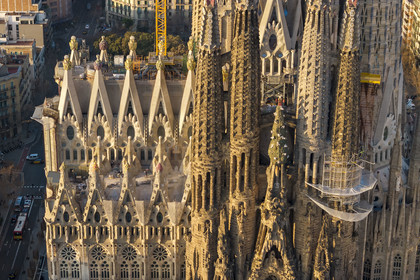 Spain, Catalonia, Barcelona, Eixample district, Sagrada Familia basilica by Catalan modernist architect Antoni Gaudi, listed as a UNESCO World Heritage Site, peaks topped with mosaics in the shape of fruits surrounding the construction site on the roof of the nave here on the Passion facade side