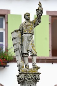 France, Haut-Rhin (68), Route des vins d'Alsace, Ribeauvillé, statue sur une fontaine d'un vigneron s'appuyant sur sa hotte et présentant dans sa main gauche une belle grappe de raisin