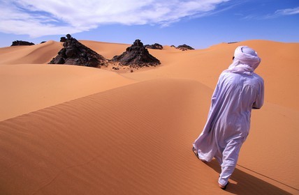 Libye, région du désert, Le Fezzan (Sahara), Touareg marchant entre les aiguilles de grès du Tassili de Maghidet (frontière algérienne)