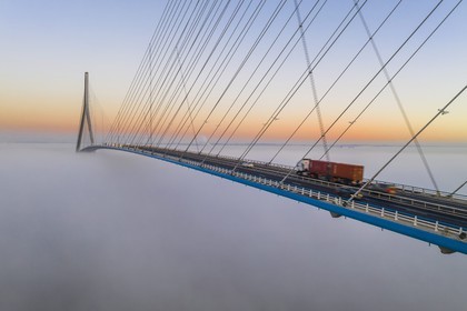 France, between  Calvados and Seine Maritime, the Pont de Normandie (Normandy Bridge) emerges from the morning mist of autumn and spans the Seine to connect the towns of Honfleur and Le Havre