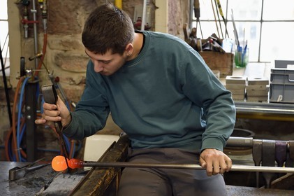 France, Moselle, Meisenthal, Centre international d'Art verrier (CIAV) (international glass centre), the blowing workshop, crafting a Christmas ball, the prompter regulates the mass at home plate while performing a continuous rotation of his cane and preparation of the parison before passing to the mold