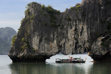 Vietnam, Quang Ninh Province, Halong Bay, listed as World Heritage by UNESCO, fishing boats under a naturel  limestone arch