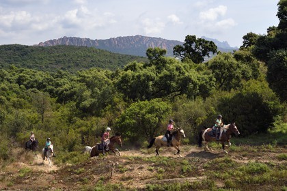 France, Var, Agay area next to Saint-Raphael, riders trekking in the Massif de l'Esterel (Esterel Massif) and the rastel of Agay in the background