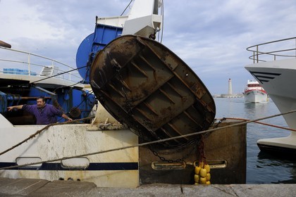 France, Herault, Sete, Vieux Port (Old harbour), docking activity on the wharf of the fish auction market and the lighthouse of the Mole St. Louis