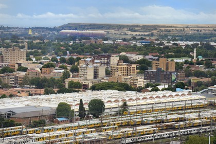Afrique du Sud, province de Gauteng, Johannesburg, les wagons de trains colorés de Park Station et le Soccer City Stadium à Soweto au pied d'un immense terril d'une mine d'or en arrière plan