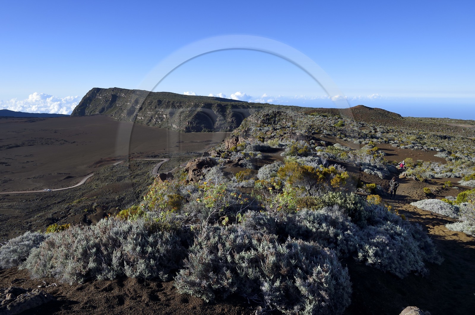France, Ile de la Reunion, Parc National de la Réunion classé Patrimoine Mondial de l'UNESCO, sur les pentes du volcan de Piton de la Fournaise, randonneurs sur le sentier de l'oratoire Ste Thérèse au dessus de la Plaine des Sables que l'on aperçoit en contrebas