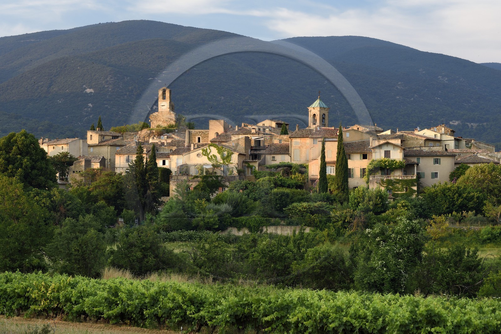 France, Vaucluse (84), Parc Naturel Regional du Luberon, Lourmarin, labellisé Les Plus Beaux Villages de France, la Tour de l'horloge et le chocher de l'église, le massif du Lubéron en arrière-plan