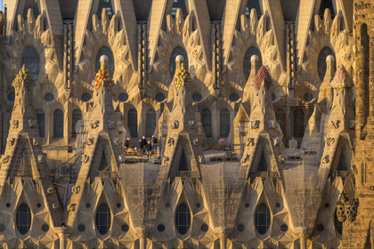 Spain, Catalonia, Barcelona, Eixample district, Sagrada Familia basilica by Catalan modernist architect Antoni Gaudi, listed as a UNESCO World Heritage Site, peaks topped with mosaics in the shape of fruits surrounding the construction site on the roof of the nave here on the Passion facade side