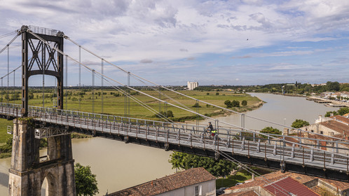 France, Charente-Maritime, Saintonge, Tonnay Charente, cyclist traveling along the Flow Vélo cycle route crossing the suspension bridge built in 1842 over the Charente river (aerial view)