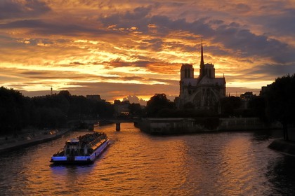 France, Paris (75), les rives de la Seine, classées Patrimoine Mondial de l'UNESCO, un bateau mouche devant la cathédrale Notre-Dame au soleil couchant