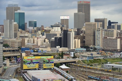 South Africa, Gauteng Province, Johannesburg, colorfull train carriages at Park Station and Johannesburg CBD in the background seen from the district of Braamfontein