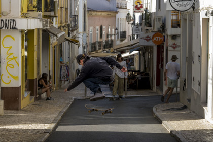 Portugal, Algarve, Lagos, Skateboarder performing a trick on Candido dos Reis street