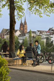 Switzerland, Canton Basel-Stadt, Basel, Little Basel district quays on the right bank of the river Rhine and the Minster or Protestant Cathedral of Our Lady of Basel (Munster) in the background, restaurant and café terraces come alive at dusk
