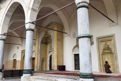 Bosnia and Herzegovina, Sarajevo, Bascarsija district in the old town, man praying outside the Gazi Husrev-bey Mosque (Gazi Husrev-begova Dzamija in bosnian)