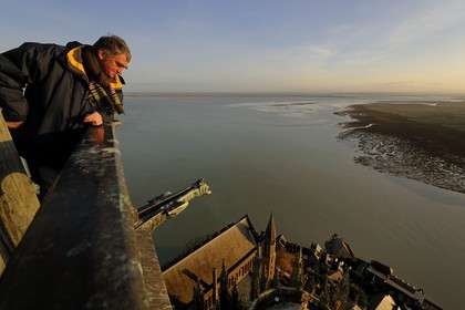 France, Manche (50), Mont-Saint-Michel, classé Patrimoine Mondial de l'UNESCO, monsieur Antoine Bacchiarotti observant le chevet et la baie vus depuis la flèche à l'aube