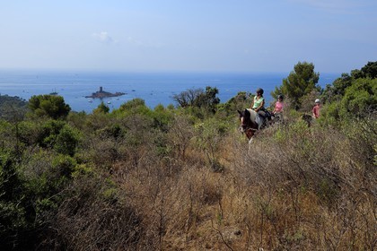 France, Var, Agay area next to Saint-Raphael, riders trekking in the Massif de l'Esterel (Esterel Massif) and the Ile d'Or island on the Dramont cape in the background