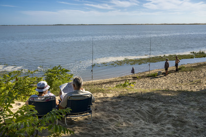 France, Charente-Maritime (17), Royan, Les Mathes, pecheurs à la ligne en bordure de la baie de Bonne Anse à marée haute et lecture du journal