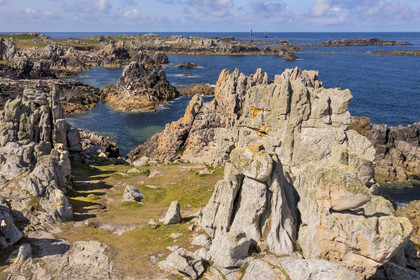 France, Finistère (29), Mer d'Iroise, Ile d'Ouessant, rochers façonnés par les tempêtes au pied du phare du Créac’h, le phare de Nividic sur la Pointe de Pern en arrière plan (vue aérienne)