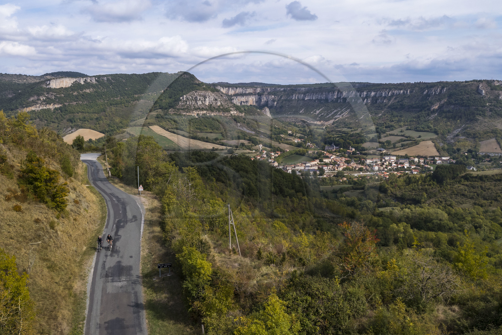 France, Aveyron (12), parc naturel régional des Grands-Causses, cyclistes effectuant l'itinéraire cyclo touristique Brebis'Cyclette en Pays de Roquefort, le village de Tournemire dans le cirque au pied du Causse du Larzac (vue aérienne)