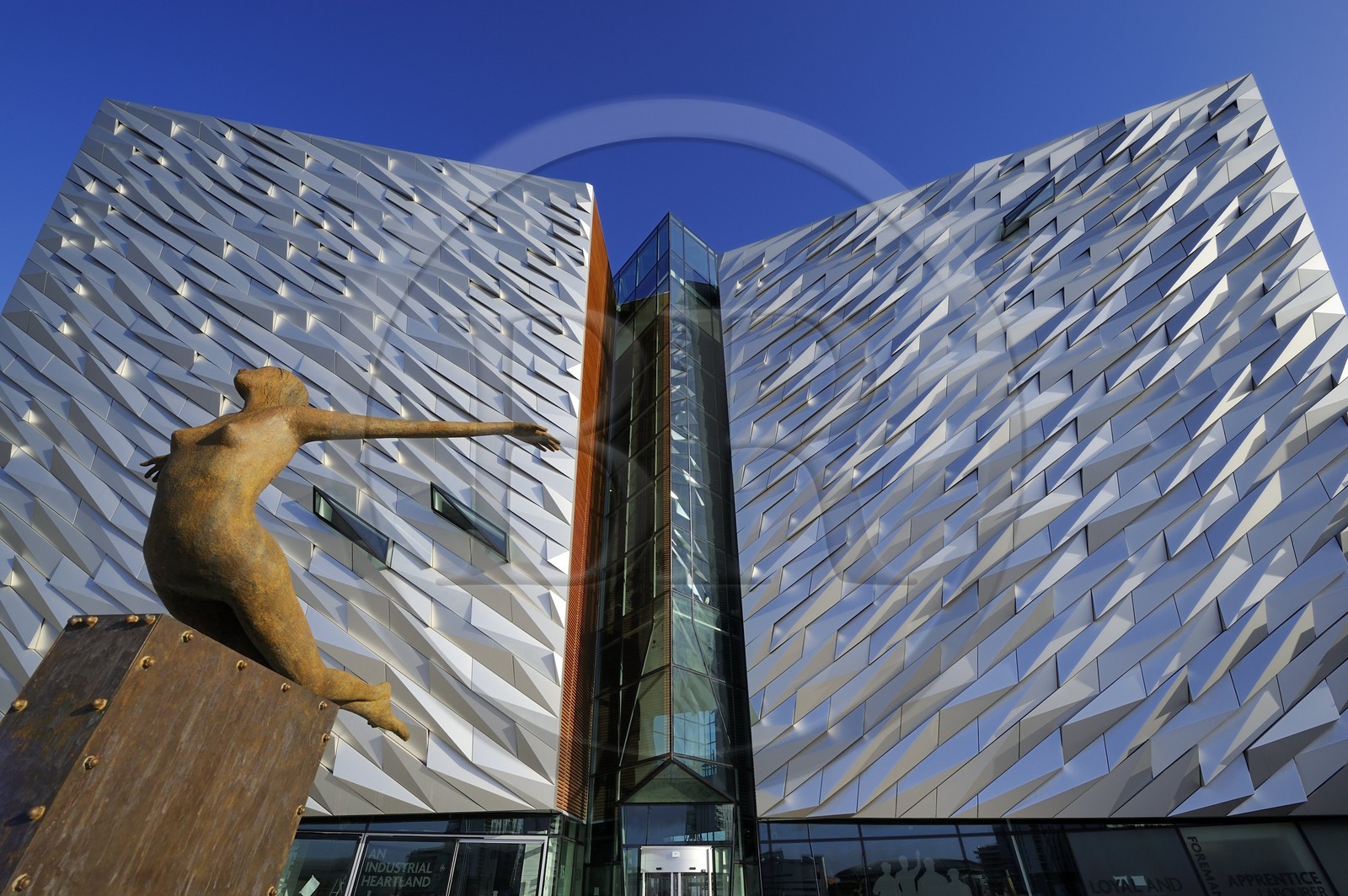 United Kingdom, Northern Ireland, Belfast, docks district of Queen's Island, Titanica sculpture by artist Rowan Gillespie in front of the Titanic Belfast Experience center building