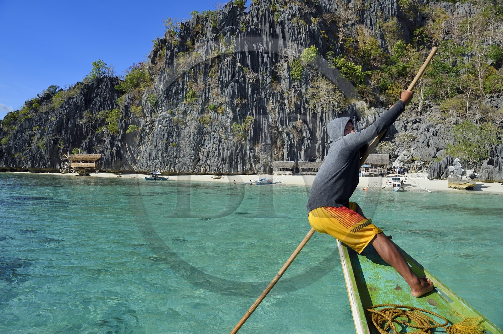 Philippines, Calamian Islands in northern Palawan, Coron Island Natural Biotic Area, Banul Beach under giant walls of limestone cliffs, boatman