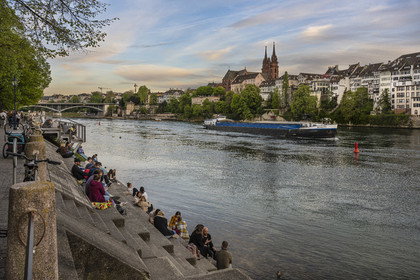 Switzerland, Canton Basel-Stadt, Basel, Little Basel district quays on the right bank of the river Rhine come alive at dusk, a barge goes down the river, the Minster or Protestant Cathedral of Our Lady of Basel (Munster) in the background