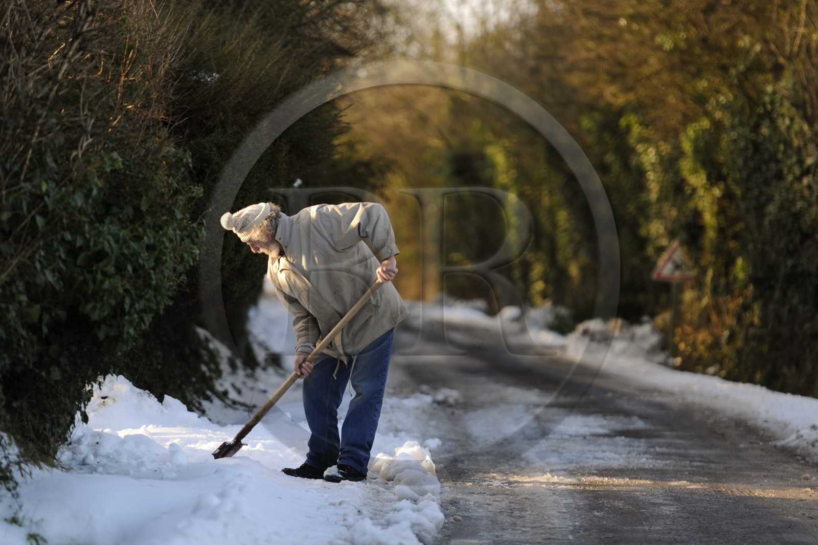 France, Manche (50), Cotentin, Sainte-Marie-du-Mont, homme déneigeant devant chez lui