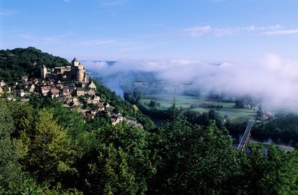 France, Dordogne, Castelnaud la Chapelle and its castle overhanging the Dordogne river in the morning fog