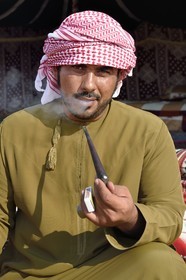 Sultanat d'Oman, gouvernorat de Ash Sharqiyah, désert des Wahiba Sands ou Sharqiya Sands, village bédouin de al-Wasil, Mohamed al-Badri fume la pipe devant sa tente