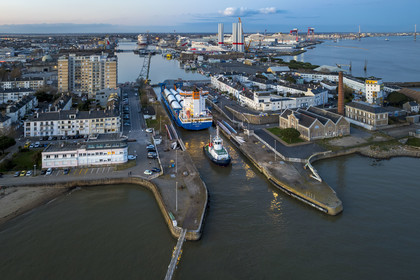 France, Loire-Atlantique (44), Saint-Nazaire, le General Cargo Rotra Mare transporte des sections des mats d'éoliennes et entre dans le bassin à flot du port (en arrière plan) par  l'écluse sud, qui est aussi le lieu de l’Opération Chariot lancée en 1942 par les Britanniques (vue aérienne)