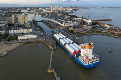 France, Loire-Atlantique (44), Saint-Nazaire, le General Cargo Rotra Mare transporte des sections des mats d'éoliennes et entre dans le bassin à flot du port (en arrière plan) par  l'écluse sud, qui est aussi le lieu de l’Opération Chariot lancée en 1942 par les Britanniques (vue aérienne)