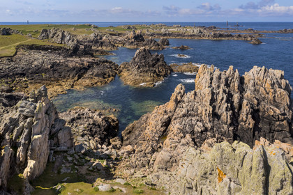 France, Finistère (29), Mer d'Iroise, Ile d'Ouessant, rochers façonnés par les tempêtes au pied du phare du Créac’h, le phare de Nividic sur la Pointe de Pern en arrière plan (vue aérienne)