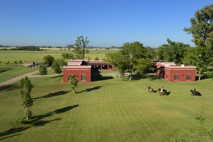 Argentine, province de Buenos Aires, San Antonio de Areco, estancia La Bamba de Areco, gauchos à cheval passant devant l'étable des chevaux utilisés pour le polo