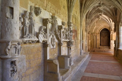 France, Dordogne,  Perigord Noir, Le Buisson de Cadouin, former cistercian abbey church, stage on the Camino de Santiago (Way of St. James) listed as World Heritage by UNESCO, the cloister of the 15th century, the Passion of Christ bas-relief, the monks bench with the seat of the Abbot and Romane door in the background