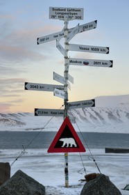 Norway, Svalbard, Spitzbergen, Longyearbyen, direction and distance signs in front of Longyearbyen Airport and warning sign of potential danger of presence of polar bear