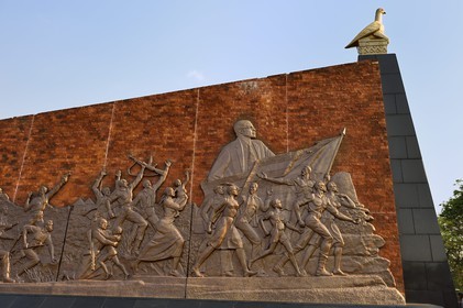 Zimbabwe, Harare, burial ground and national monument to commemorate Patriotic Front guerrillas killed during the Rhodesian Bush War, wall carrying murals depicting the history of Zimbabwe, here the independence movement under national hero Robert Mugabe and the stone-carved Zimbabwe Bird on the top