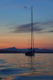 France, Var, Iles d'Hyeres, Parc National de Port Cros (National park of Port Cros), Porquerolles island, boat at anchor at dusk, the Giens peninsula and Mont Coudon in the background