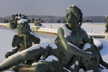 France, Yvelines, snow covered park of the Chateau de Versailles, listed as World Heritage by UNESCO, statue on the Parterre d'eau