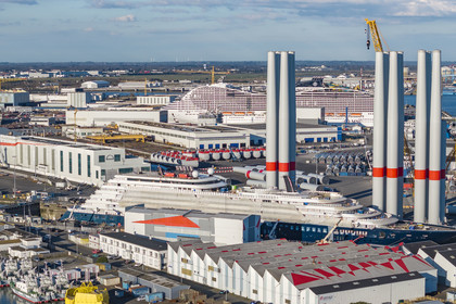France, Loire-Atlantique (44), Saint-Nazaire, le chantier du super-yacht de luxe Ritz-Carlton Luminara dans la forme Joubert au premier plan, les tours d'éoliennes sont stockées avant embarquement, le paquebot de 333m MSC World America construit par les Chantiers de l'Atlantique en arrière plan (vue aérienne)