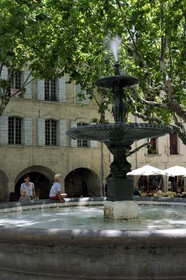 France, Gard, Uzes, listed as town of art and history, fountain of the Place aux Herbes surrounded by arcaded houses and its outdoor cafes