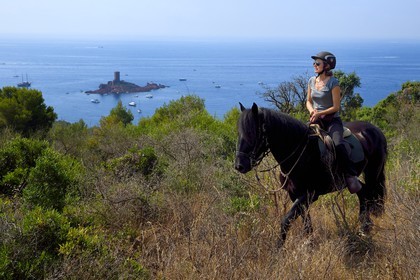 France, Var, Agay area next to Saint-Raphael, riders trekking in the Massif de l'Esterel (Esterel Massif) and the Ile d'Or island on the Dramont cape in the background