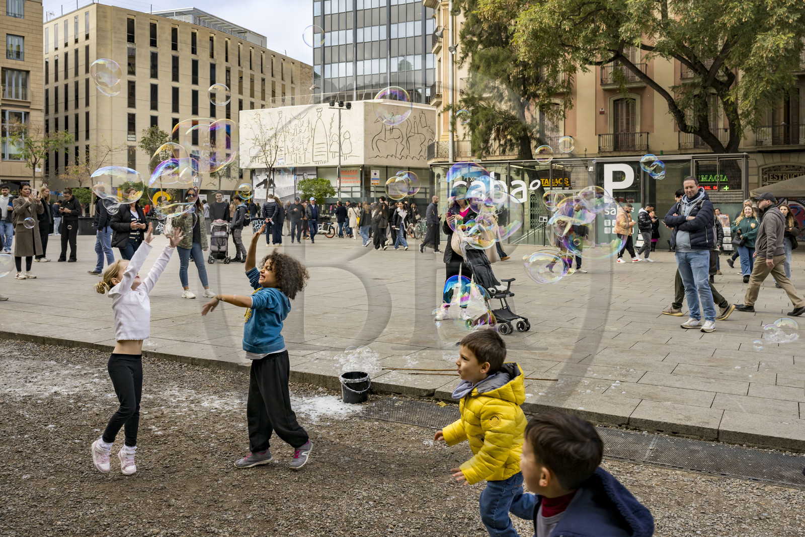 Espagne, Catalogne, Barcelone, quartier du Barrio Gotico, enfants jouant sur la placa Nova, les frises dessinées par Pablo Picasso pour l'immeuble de l'Ordre des Architectes de Catalogne en arrière plan
