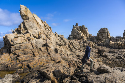 France, Finistère (29), Mer d'Iroise, Ile d'Ouessant, randonneuse dans les rochers façonnés par les tempêtes au pied du phare du Créac’h