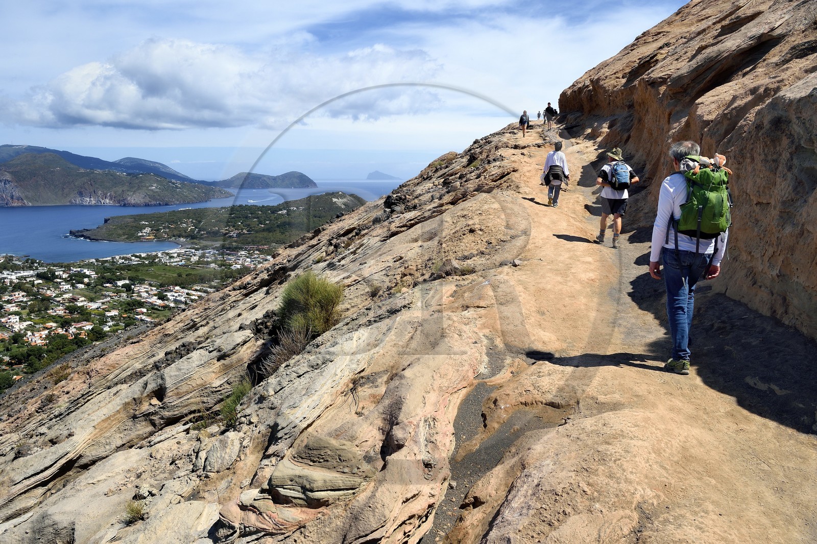 Italy, Sicily, Aeolian Islands, listed as World Heritage by UNESCO, Vulcano Island, hikers climbing the crater of volcano della Fossa, passage over volcanic tuff and Lipari Island in the background