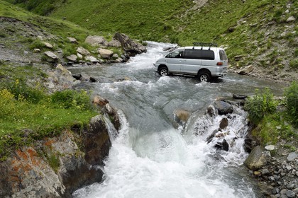Georgia, Kakheti, Tusheti National Park, Alazani River Valley in the mountains of Pirikiti, car crossing the river fording